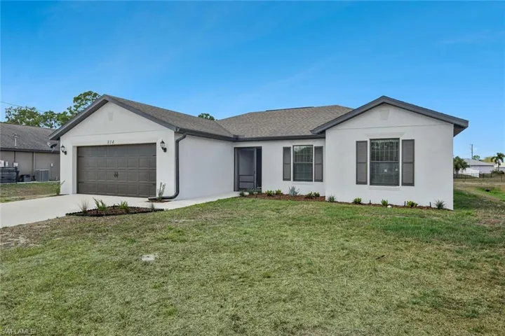 Single story home featuring a front lawn, stucco siding, driveway, and an attached garage