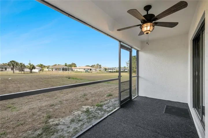 Unfurnished sunroom featuring a ceiling fan and a residential view