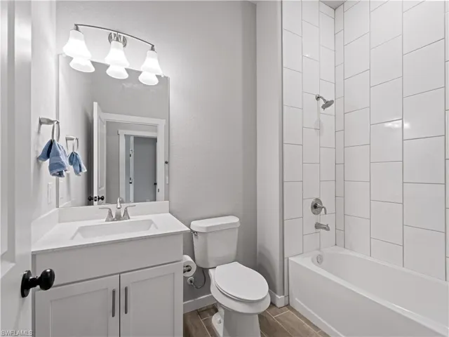 Full bathroom featuring tile floors, tiled shower / bath combo, vanity, and toilet