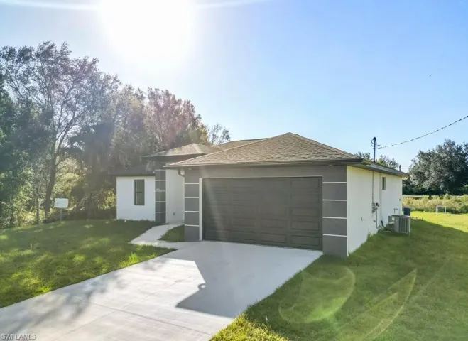 Single story home with a garage, a front yard, and central air condition unit