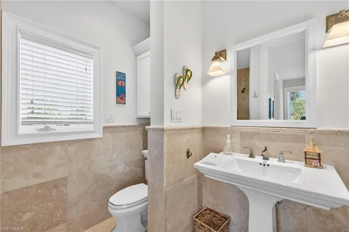 Full bathroom featuring tile walls, wainscoting, and a shower