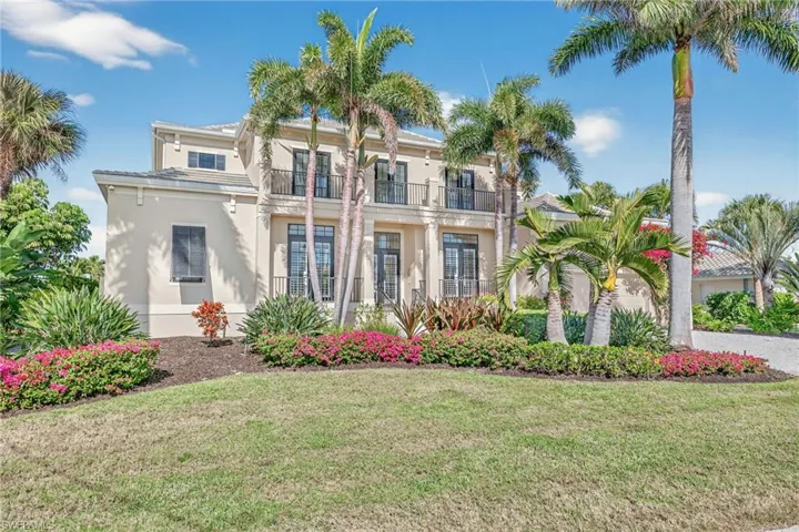 View of front of home featuring a balcony, stucco siding, and a front lawn