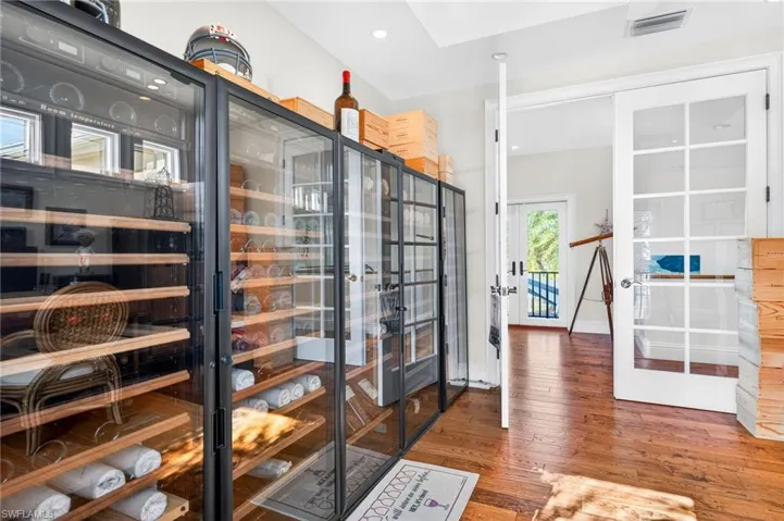 Wine area featuring beverage cooler, french doors, wood-type flooring, and recessed lighting