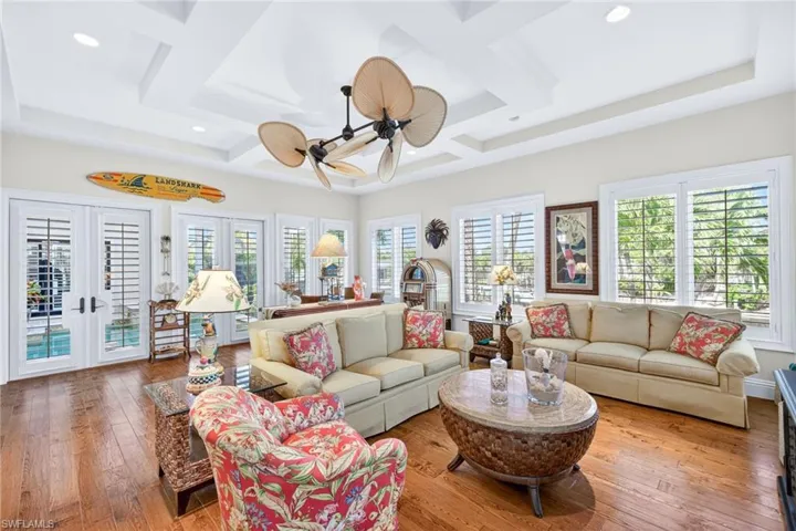 Living area with french doors, coffered ceiling, wood-type flooring, a ceiling fan, and beam ceiling