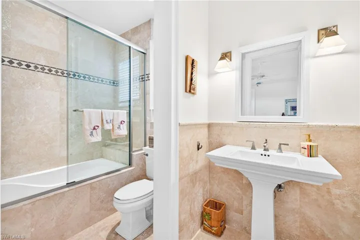 Full bath with tiled shower / bath, tile walls, and wainscoting