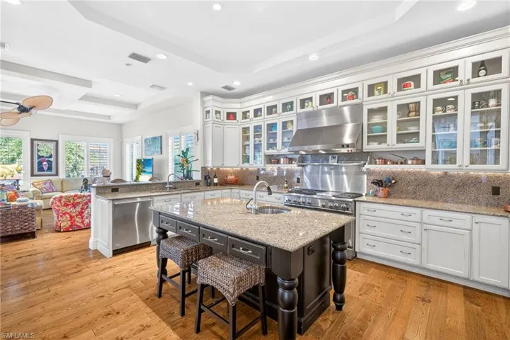 Kitchen featuring a kitchen bar, open floor plan, a peninsula, light stone countertops, and white cabinets