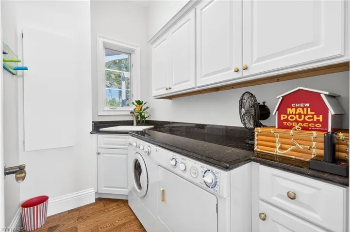 Laundry area with dark wood-style flooring, cabinet space, and washing machine and dryer