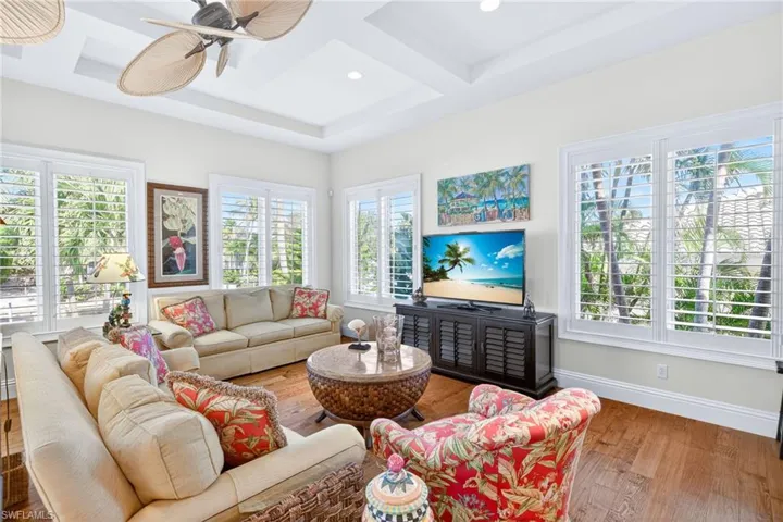 Living room featuring coffered ceiling, wood finished floors, a ceiling fan, and beam ceiling
