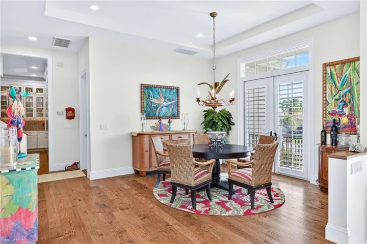 Dining space with a raised ceiling, light wood-type flooring, a chandelier, and recessed lighting