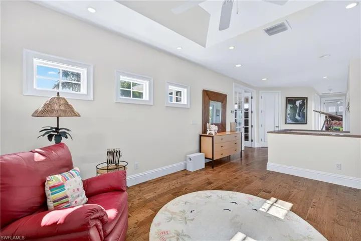 Living area with wood finished floors, plenty of natural light, recessed lighting, and a ceiling fan