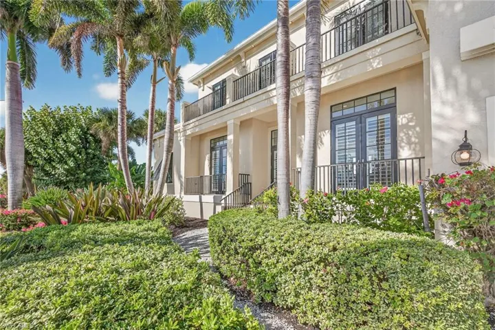 View of front of home featuring stucco siding, a balcony, a wall unit AC, and french doors