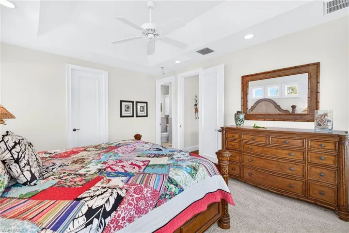 Carpeted bedroom with recessed lighting, a ceiling fan, a raised ceiling, and connected bathroom