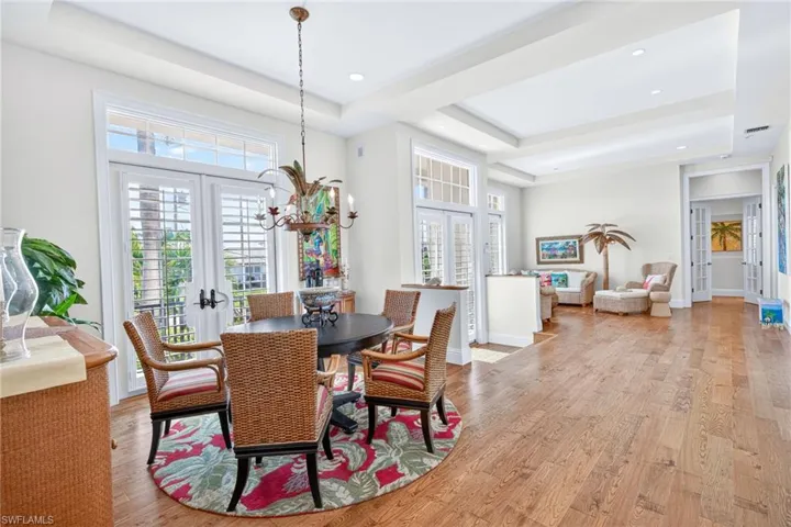 Dining space featuring french doors, a raised ceiling, light wood-type flooring, and recessed lighting