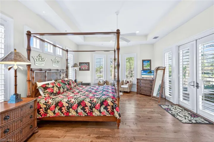 Bedroom with access to exterior, wood finished floors, a tray ceiling, and recessed lighting