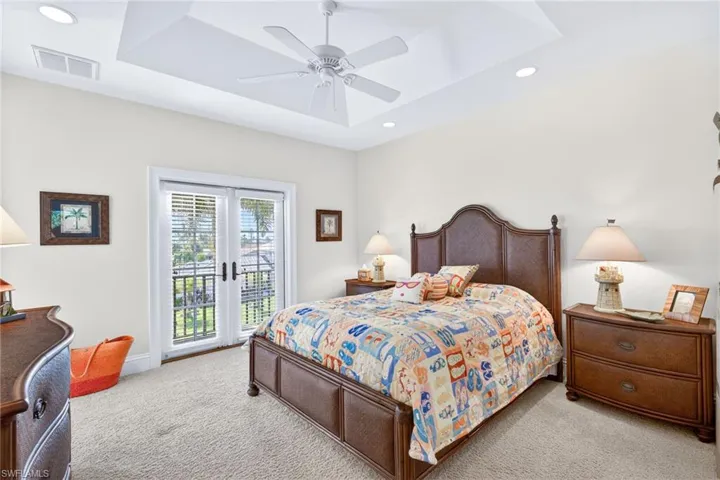Bedroom with a tray ceiling, access to outside, carpet floors, a ceiling fan, and recessed lighting