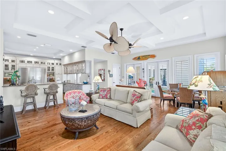 Living room with a ceiling fan, light wood-type flooring, recessed lighting, coffered ceiling, and a raised ceiling