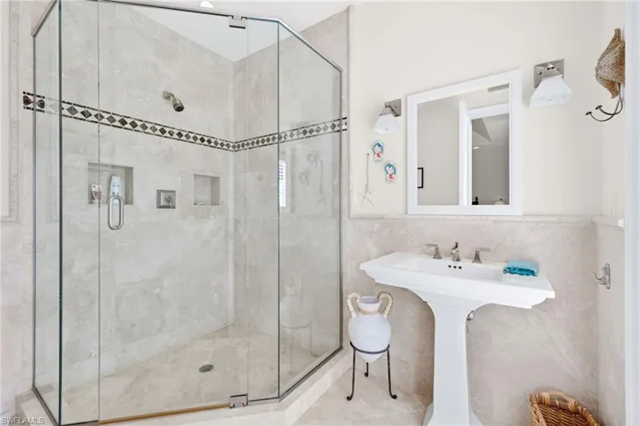 Full bathroom featuring tile walls, a stall shower, and a wainscoted wall