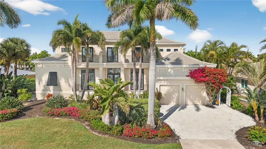 View of front of home with driveway, stucco siding, and a balcony