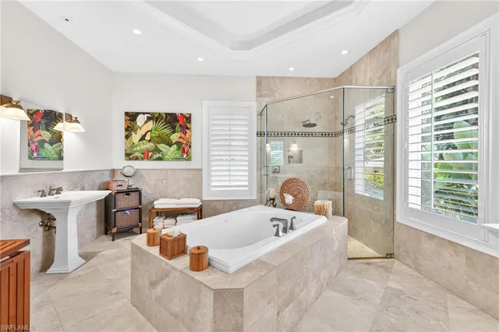 Bathroom with a bath, tile walls, a stall shower, wainscoting, and recessed lighting