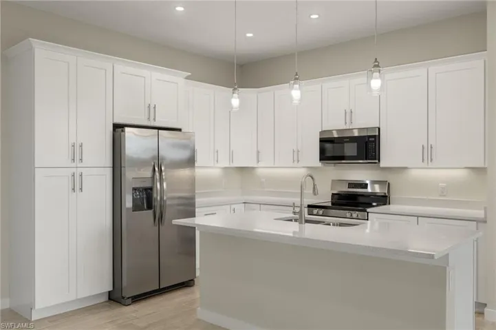Gourmet kitchen with quartz island, shaker cabinets, and premium luxury vinyl plank (LVP) flooring upgrade.