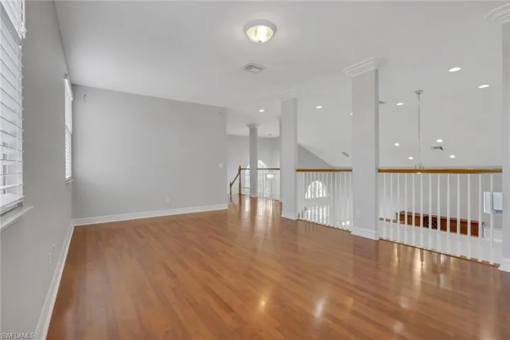 Spare room with wood finished floors and decorative columns