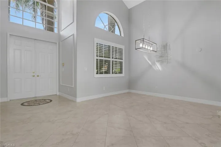 Foyer entrance featuring a high ceiling, hanging lights, and plenty of natural light