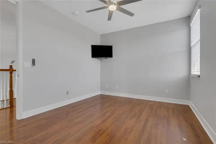 Unfurnished room featuring wood finished floors, a ceiling fan, and vaulted ceiling