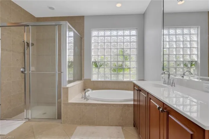 Bathroom with vanity, light tile patterned flooring, a shower stall, healthy amount of natural light, and recessed lighting