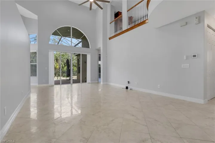Unfurnished living room featuring a high ceiling and ceiling fan