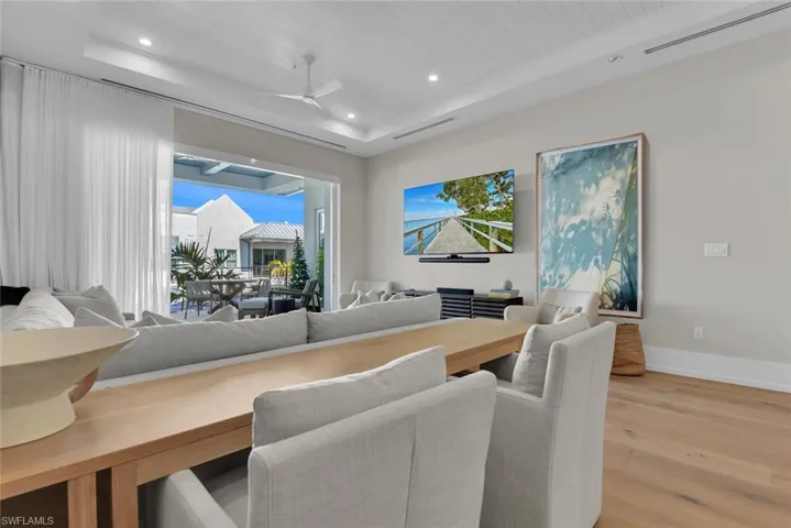 Dining space with a raised ceiling, light wood-type flooring, ceiling fan, recessed lighting, and baseboards