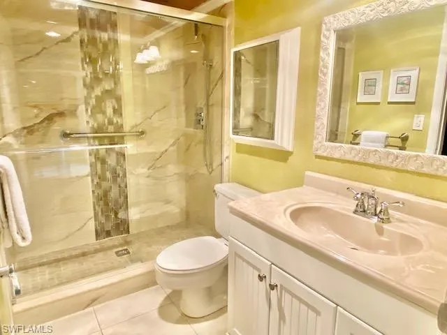 Full bath featuring a shower stall, tile patterned flooring, vanity, and toilet