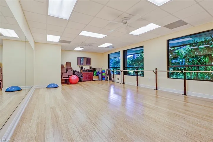 Workout area with a paneled ceiling, wood finished floors, and ceiling fan