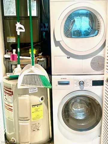 Clothes washing area featuring stacked washing maching and dryer and laundry area