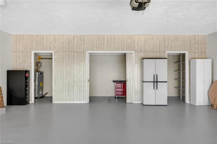 Garage with a garage door opener, wooden walls, and electric water heater