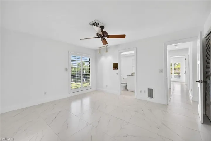 Unfurnished bedroom featuring multiple windows, ceiling fan, and light marble finish flooring