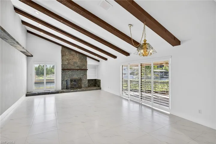 Unfurnished living room with lofted ceiling, a chandelier, and a fireplace