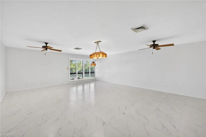 Spare room with a ceiling fan, wooden walls, and light marble finish floors