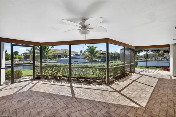 Unfurnished sunroom with a ceiling fan, a water view, and a patio area