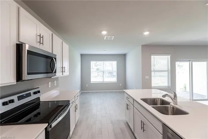 Kitchen featuring appliances with stainless steel finishes, white cabinetry, sink, and light hardwood / wood-style floors