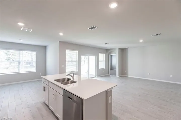 Kitchen featuring light hardwood / wood-style floors, stainless steel dishwasher, an island with sink, white cabinets, and sink