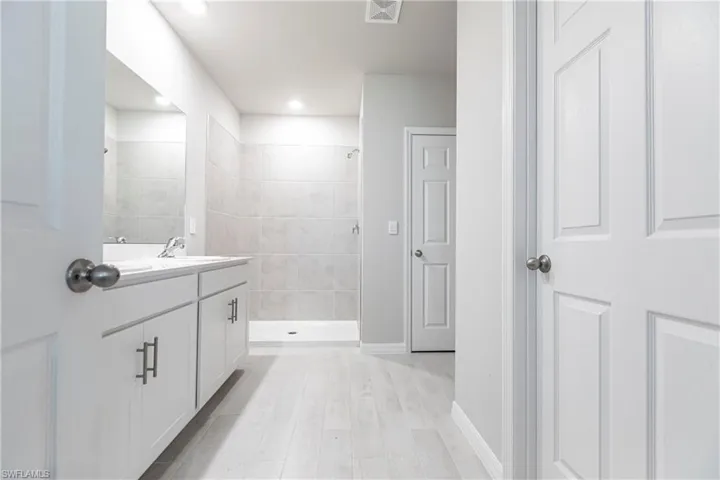 Bathroom with tiled shower, vanity, and hardwood / wood-style flooring