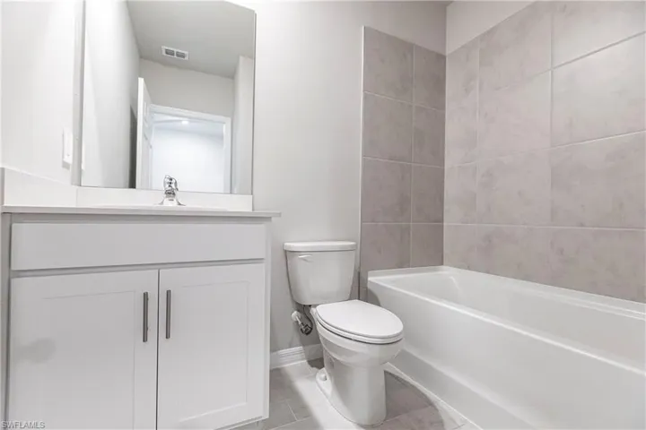 Full bathroom with tile floors, tiled shower / bath, toilet, and vanity with extensive cabinet space