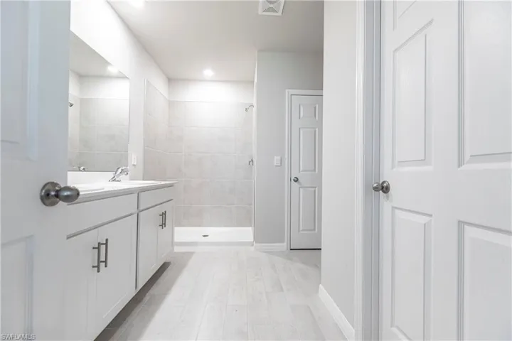 Bathroom featuring tiled shower and vanity
