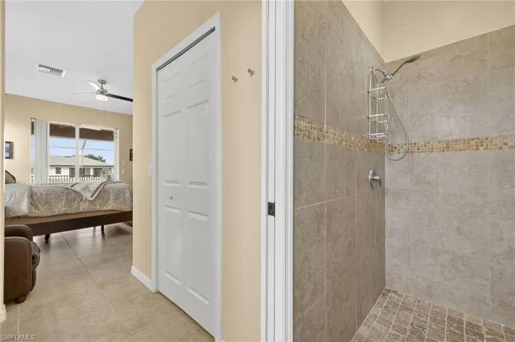 Ensuite bathroom featuring a tile shower and a ceiling fan