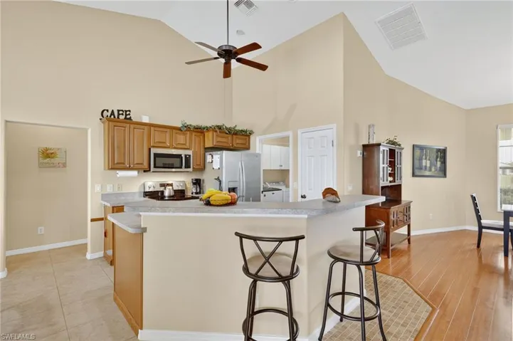 Kitchen featuring stainless steel appliances, washer and dryer, high vaulted ceiling, a ceiling fan, and light countertops