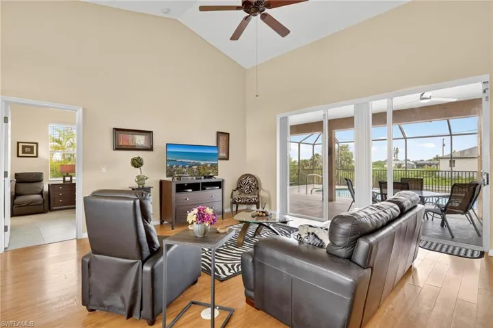 Living area featuring a ceiling fan, high vaulted ceiling, light wood-style floors, and a sunroom