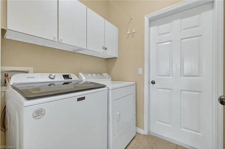Laundry area with washer and clothes dryer, cabinet space, and light tile patterned floors