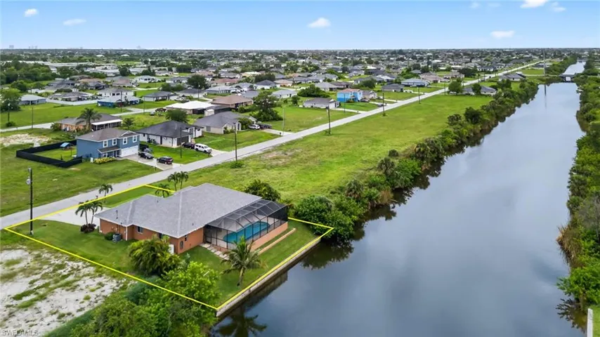 Aerial view of residential area featuring a large body of water and property boundaries highlighted