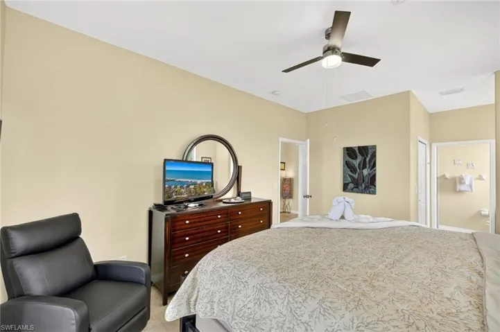 Bedroom featuring light carpet, ceiling fan, and ensuite bath