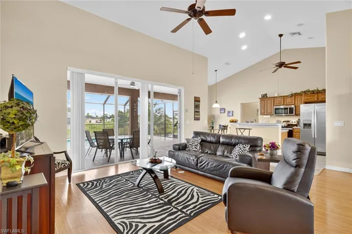 Living room featuring a ceiling fan, high vaulted ceiling, light wood-style floors, and recessed lighting